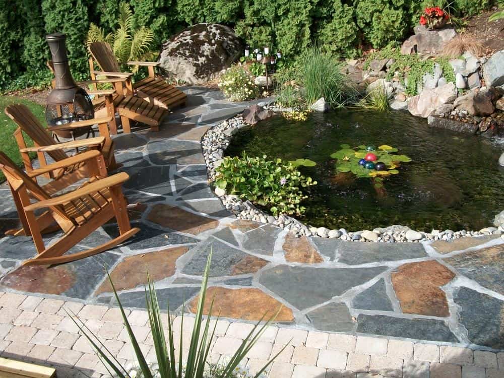Backyard retreat built around a stream and waterfall water feature by Father Nature Landscapes