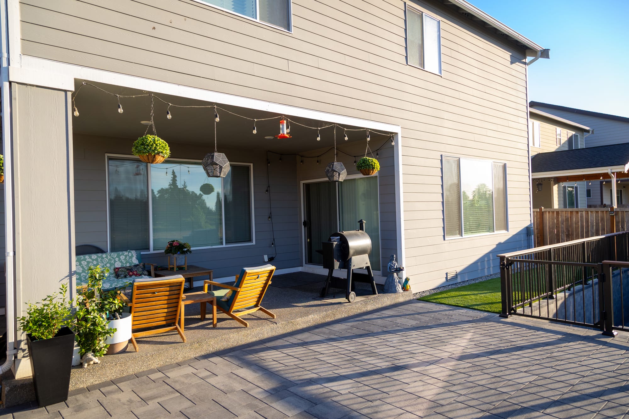 A full view of the back of the house looking across the finished upper patio, railing, and turf