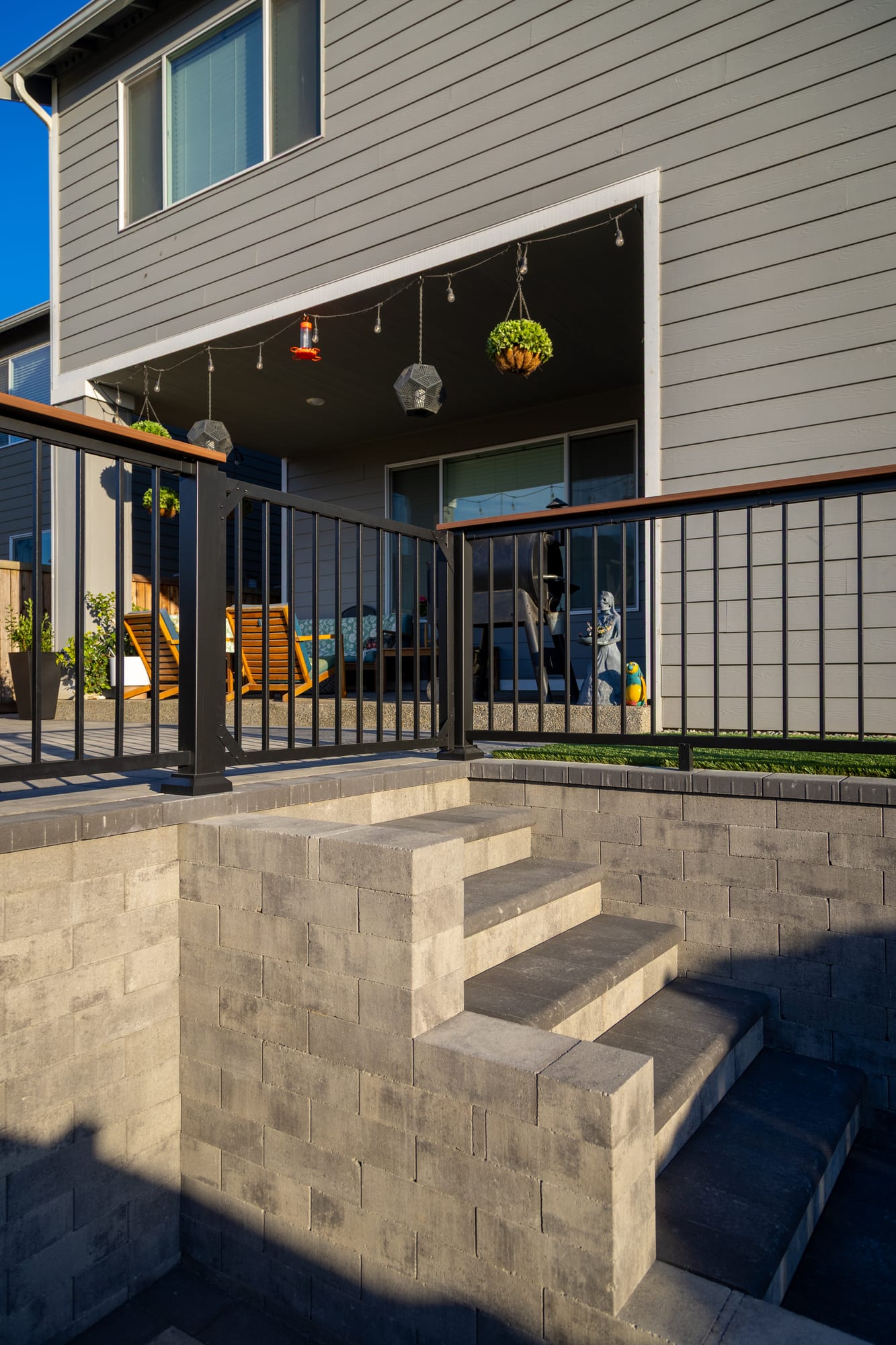 Paver steps with bullnosed coping treads climbing from the lower patio to the upper level, framed by black aluminum railing