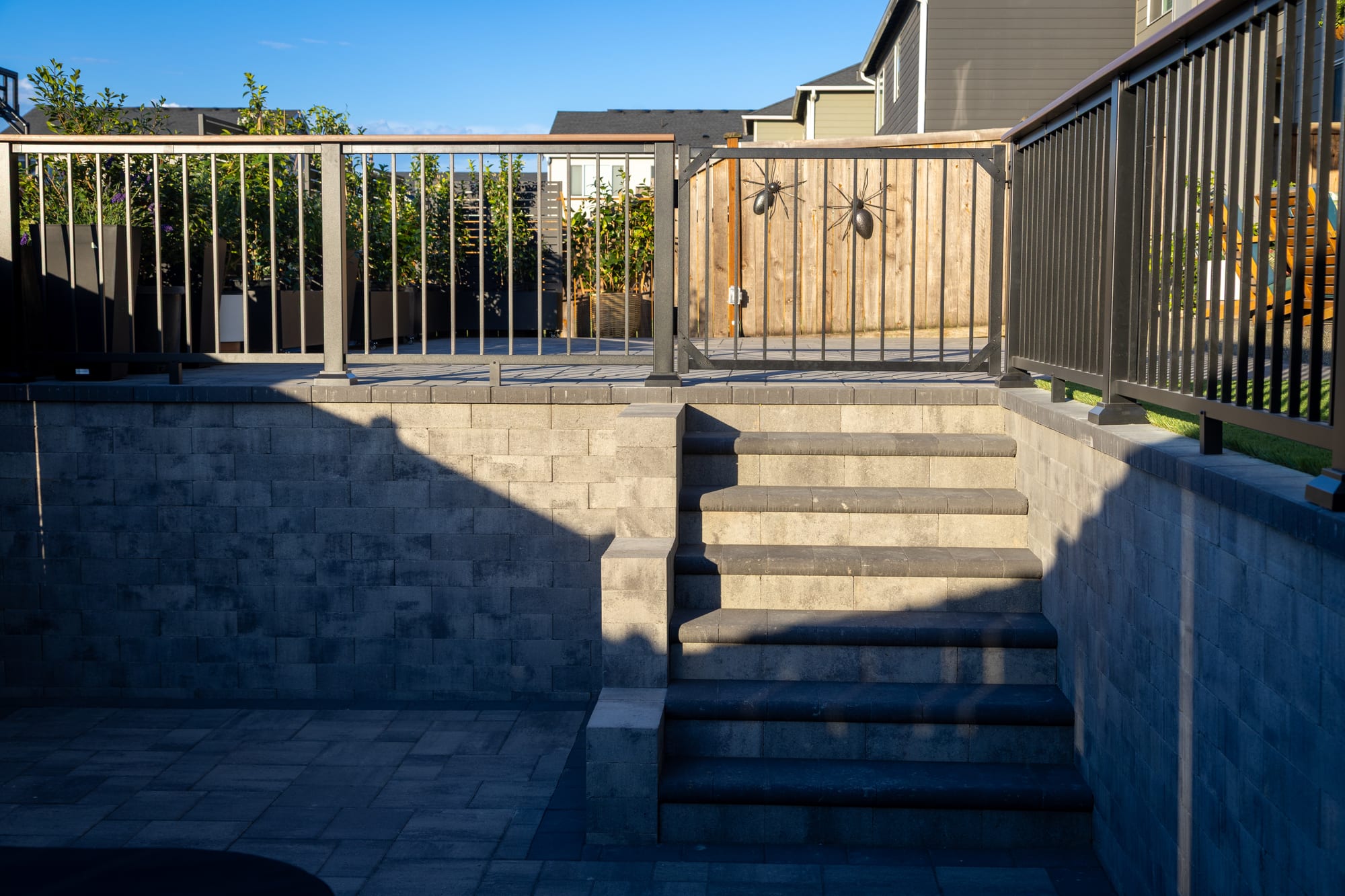 Paver stairs rising between retaining walls to a cedar gate, flanked by aluminum railing