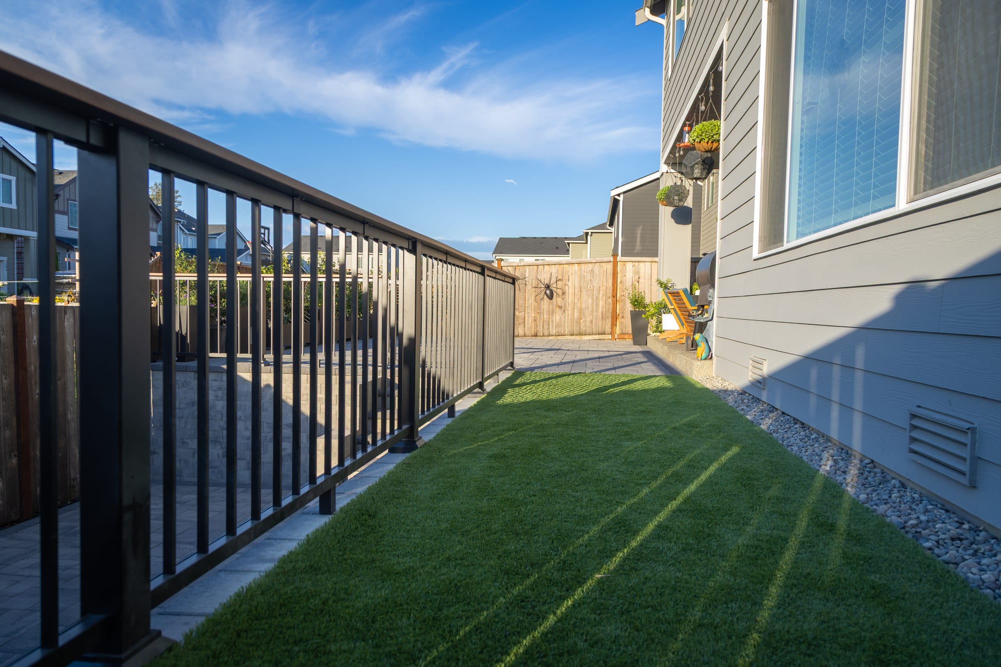 A strip of synthetic turf running between the house and the aluminum railing along the upper level