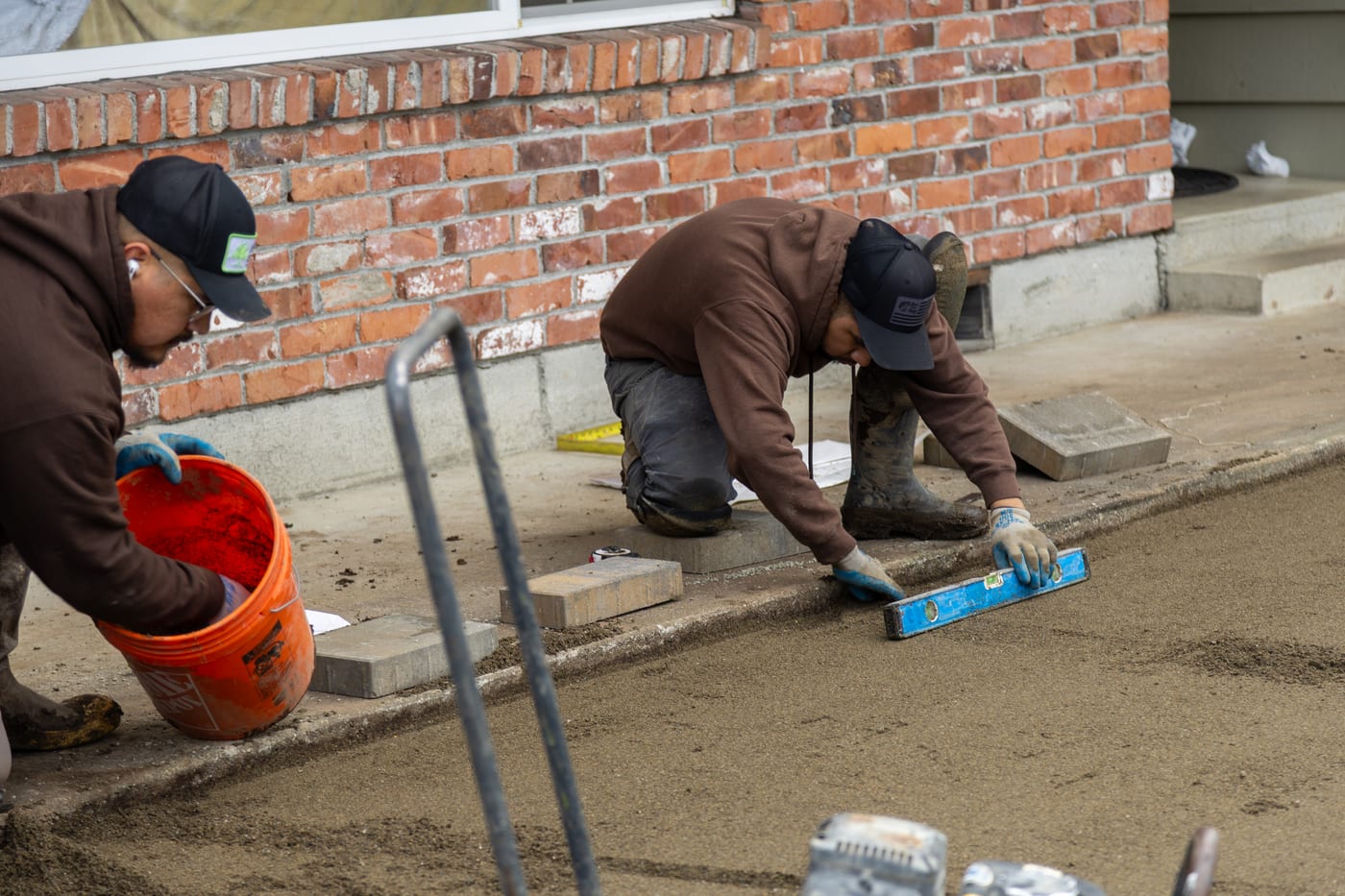 A Father Nature crew member setting pavers by hand against the house